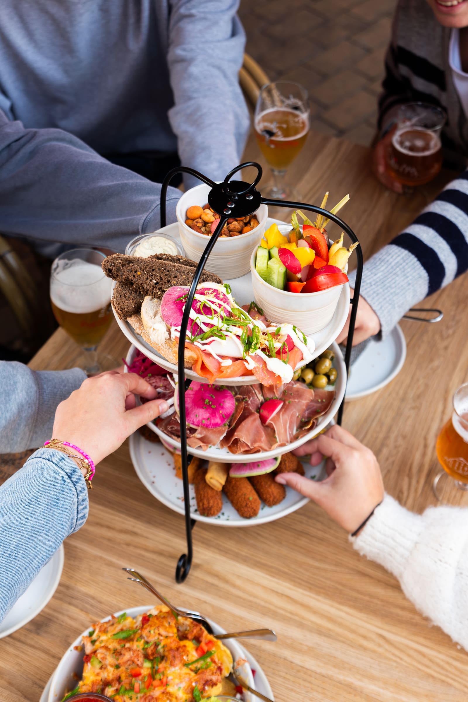 Borrelplank op etagère, van boven, met handen en bier