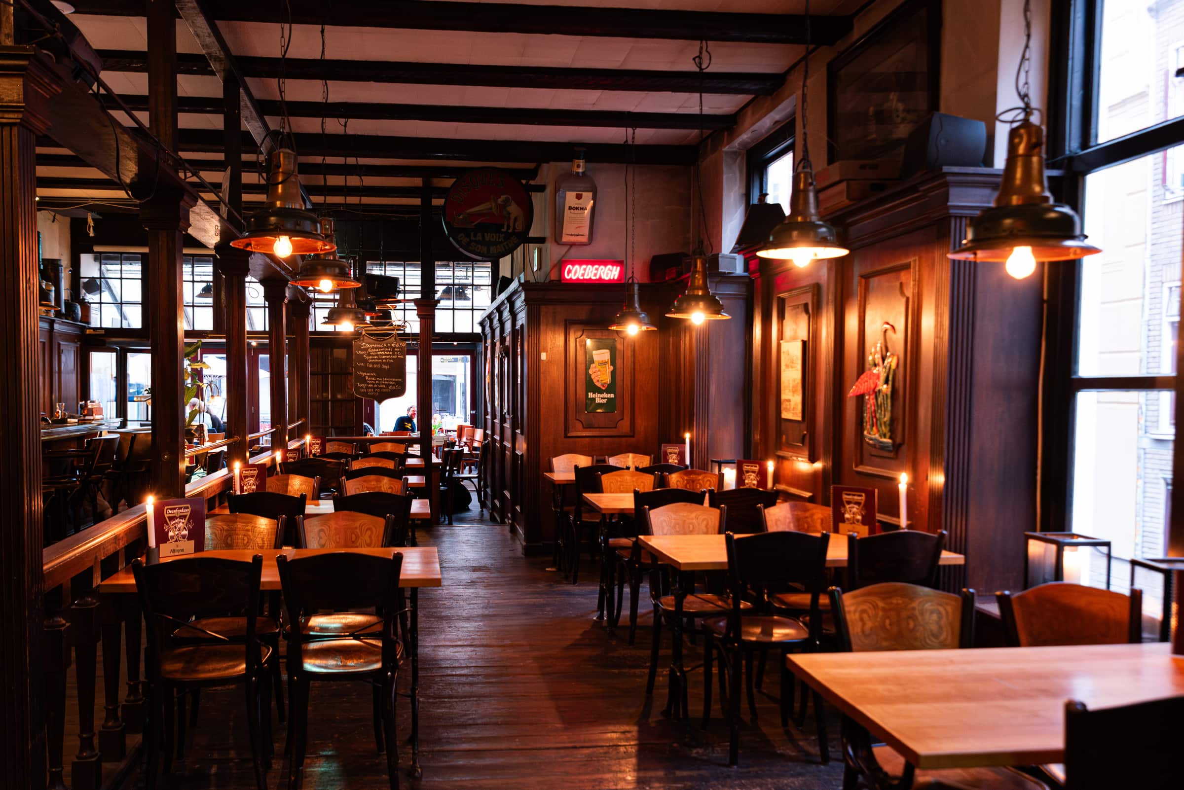 De zaal van Eetcafé Stadtlander in de avond: houten tafels, warme lampen en donker houtwerk