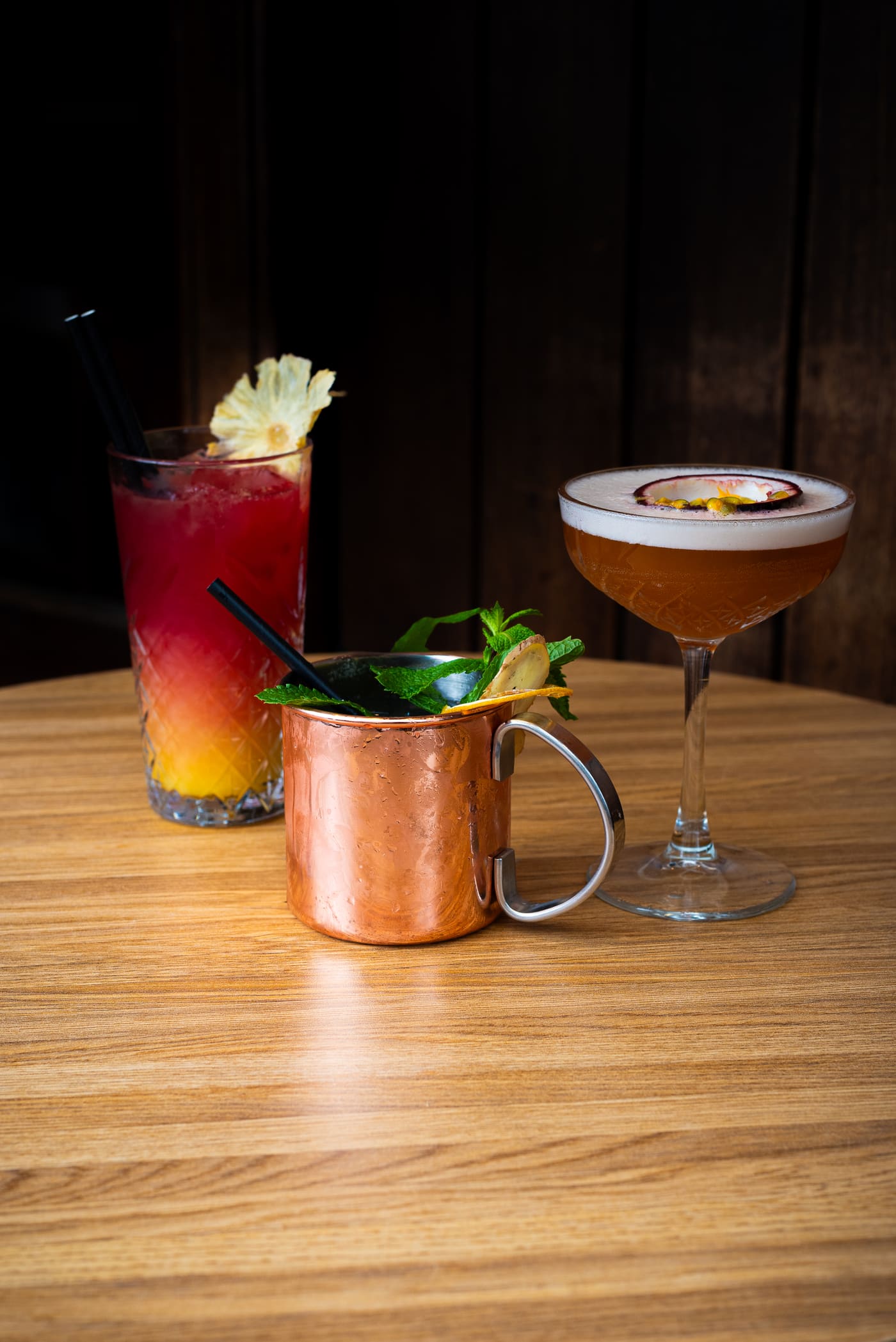 Drie cocktails in het donker, waaronder een koperen Moscow Mule-beker
